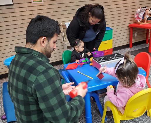 Two parents and two children sitting at a table working on an activity.